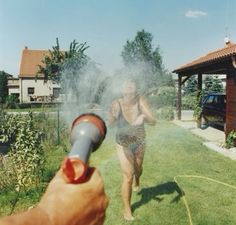 a person sprays water on their body in the backyard with a blow dryer