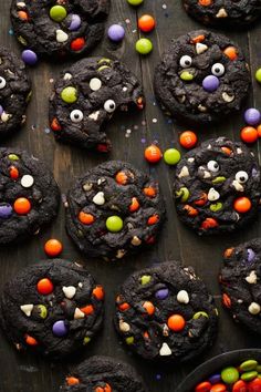 chocolate cookies decorated with candy eyes and candies on a wooden table, ready to be eaten