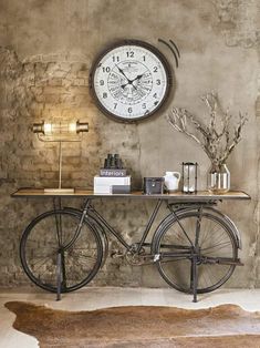 a bicycle is parked in front of a clock on the wall next to a table