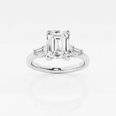 an emerald - cut diamond ring with baguets on the shoulders and side stones