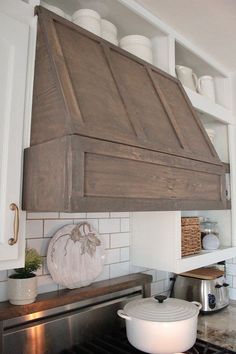 a kitchen stove with an oven hood over it's burner and pots on the shelf