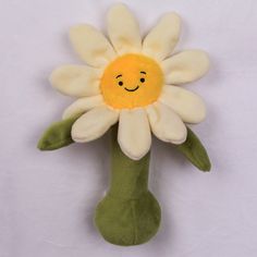 a stuffed flower with a smiley face on it's head, sitting on a white surface