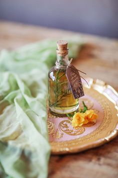 a bottle of olive oil sitting on top of a plate with yellow flowers in it