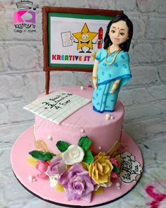 a cake with a woman standing on top of it and flowers around the edges, in front of a brick wall