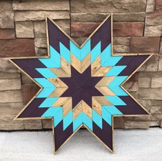 a large wooden star with blue and brown stripes on it's center is standing in front of a brick wall