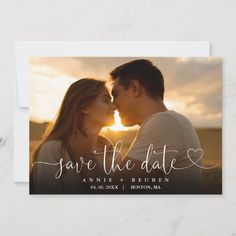 save the date card with an image of two people kissing in front of the sun