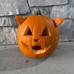 a carved pumpkin with a cat's head on it sitting in front of a brick wall