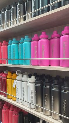 many different colored water bottles on shelves in a store