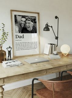 a wooden desk topped with a laptop computer next to a lamp and a framed photo