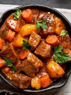 beef stew with carrots, potatoes and parsley in a cast iron skillet