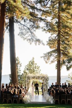 a couple getting married in front of an outdoor wedding ceremony with trees and water behind them