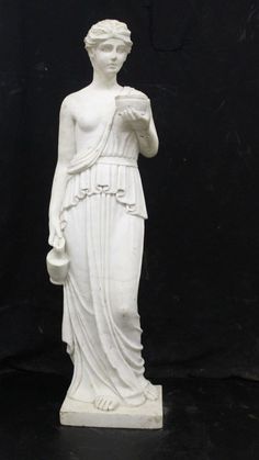 a white statue is standing on a black surface and it looks like she's holding something in her hand