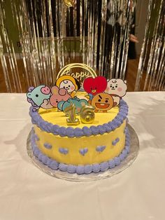 a yellow and blue cake with cartoon characters on it sitting on top of a table