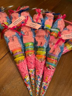 candy cones are wrapped in pink paper and tied with red ribbon on a wooden table