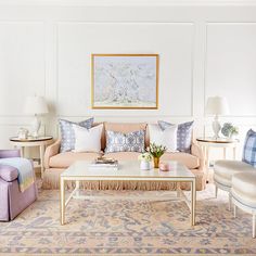 a living room filled with lots of furniture next to a painting on the wall above a coffee table