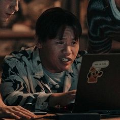 two men looking at a laptop screen with an angry look on their face and mouth