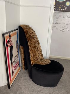 a leopard print chair sitting next to a poster