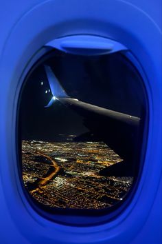 an airplane window looking out at the city lights