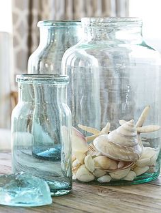 three glass jars with seashells in them