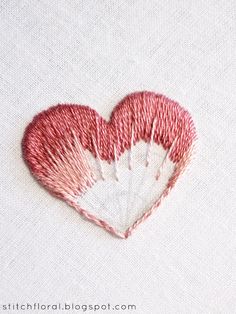 a heart - shaped piece of red thread on white fabric