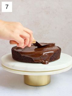 a person spreading chocolate frosting on top of a cake