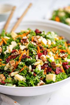 a salad with carrots, cranberries and nuts in a white bowl