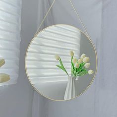 a mirror hanging on the wall with flowers in it