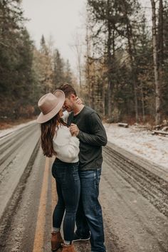 a man and woman standing in the middle of a road with snow on the ground