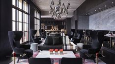 a living room filled with black furniture and lots of windows covered in chandeliers