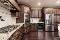 a large kitchen with wooden cabinets and stainless steel appliances in the center, along with marble counter tops