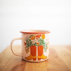 an orange and white coffee cup sitting on top of a wooden table