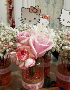 pink and white flowers in vases with hello kitty decorations on the wall behind them