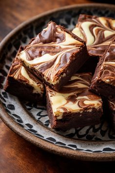 chocolate brownies with white frosting on a black and white plate sitting on a wooden table