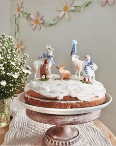 a cake with frosting and figurines of animals on it sitting on a table