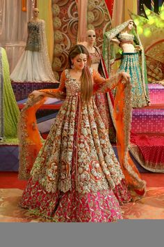 a woman in an orange and pink dress standing next to two mannequins