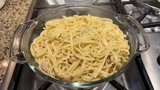 a glass bowl filled with pasta on top of a stove