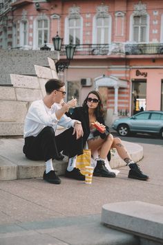 a man and woman sitting on steps in front of a building