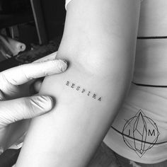 a woman with a tattoo on her arm that says respira in cursive writing