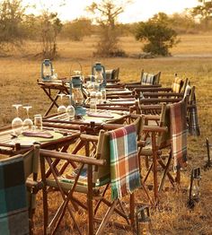 there are many chairs and tables set up in the field for an outdoor dinner party