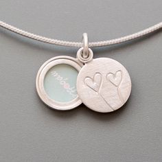 This romantic locket, handmade in solid sterling silver, is a wonderful gift, for example to celebrate your anniversary. The two hearts on the lid of the locket symbolise love and friendship. When you slide the lid to the side it reveals your favorite picture or a hidden message for your loved one. Locket for one picture - diameter small 14mm (0,55") - thickness: ca. 3,5mm (0,13") - design: two hearts  - Sterling Silver How it works: The lockets consist of two movable parts, fitting tightly toge Sterling Silver Locket Necklace For Wedding On Valentine's Day, Silver Double Heart Locket Necklace, Personalized Double Heart Sterling Silver Locket Necklace, Double Heart Locket Necklace For Anniversary, Sterling Silver Heart Pendant Locket For Wedding, Sterling Silver Pendant Locket For Wedding, Sterling Silver Charms Locket Necklace For Keepsake, Sterling Silver Locket Necklace For Wedding, Silver Double Heart Jewelry With Initials