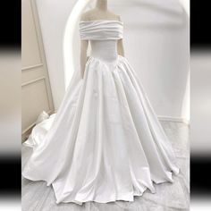 a white wedding dress is displayed on a mannequin headdress in front of a mirror