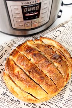 a loaf of bread sitting on top of a newspaper next to an instant pot roaster