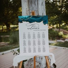 an easel with a welcome sign on it sitting in front of a wooden tree