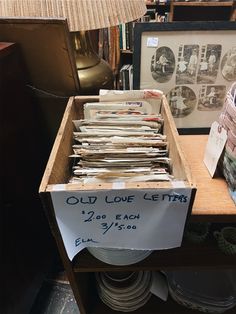 old love letters are stacked in a wooden box on a table next to a lamp