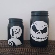 two jars with painted faces on them sitting on a table