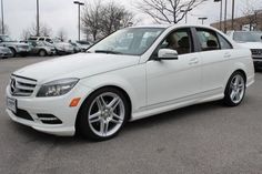 a white mercedes c - class parked in a parking lot with other cars behind it