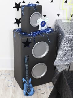 two speakers are stacked on top of each other in front of a table with black and silver decorations