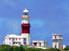 a red and white lighthouse on top of a hill