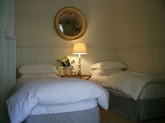 two beds in a room with white sheets and pillows