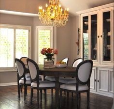 a dining room table with white chairs and a chandelier hanging from the ceiling